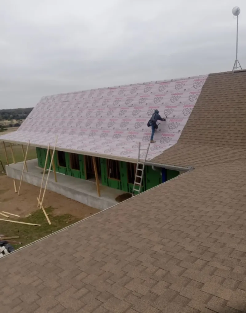 Worker preparing underlayment for a metal roof installation in Golden Valley